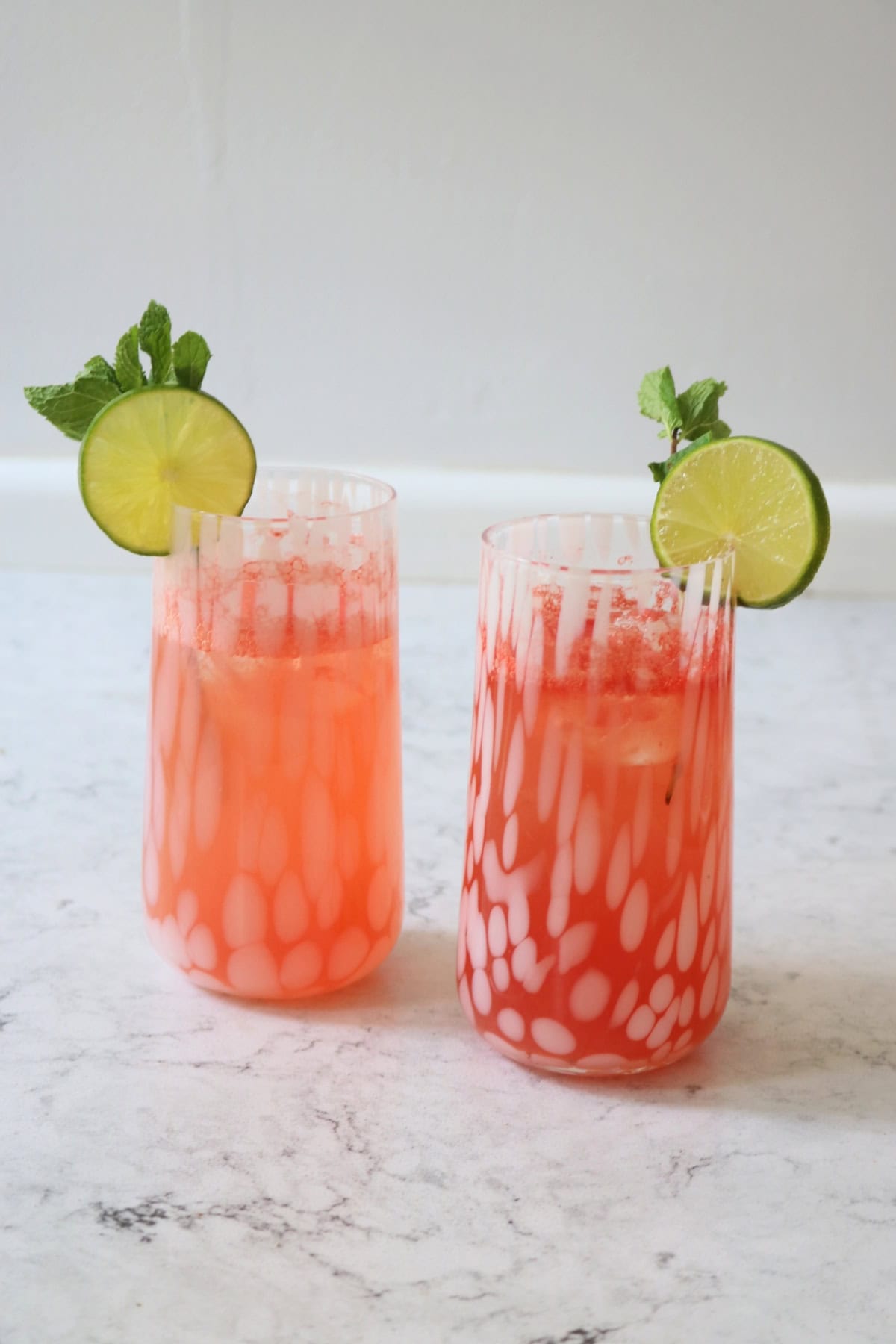 Two tall glasses of Watermelon Agua Fresca garnished with lime wheels and mint