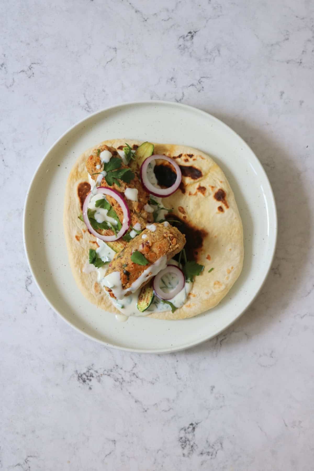 2 Vegan Tofu Kofta with mint yogurt, red onion and baby courgettes served on a flatbread
