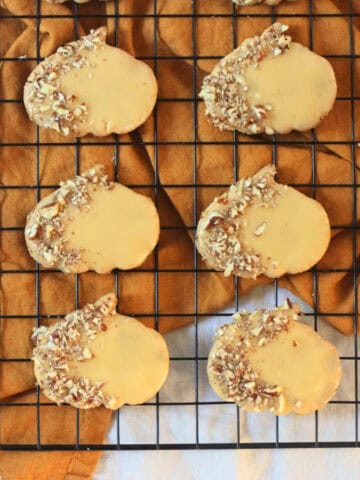 6 Vegan Pumpkin Spice and Pecan Cookies on a wire rack with an orange napkin