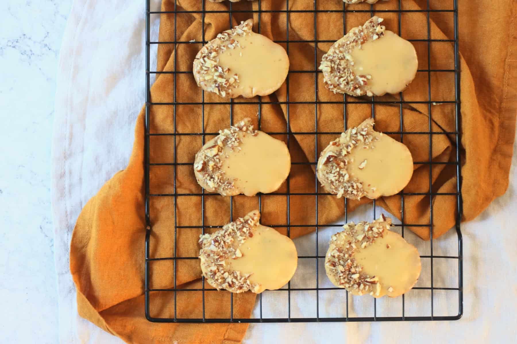 Decorated Vegan Pumpkin Spice and Pecan Cookies on a wire rack with an orange napkin