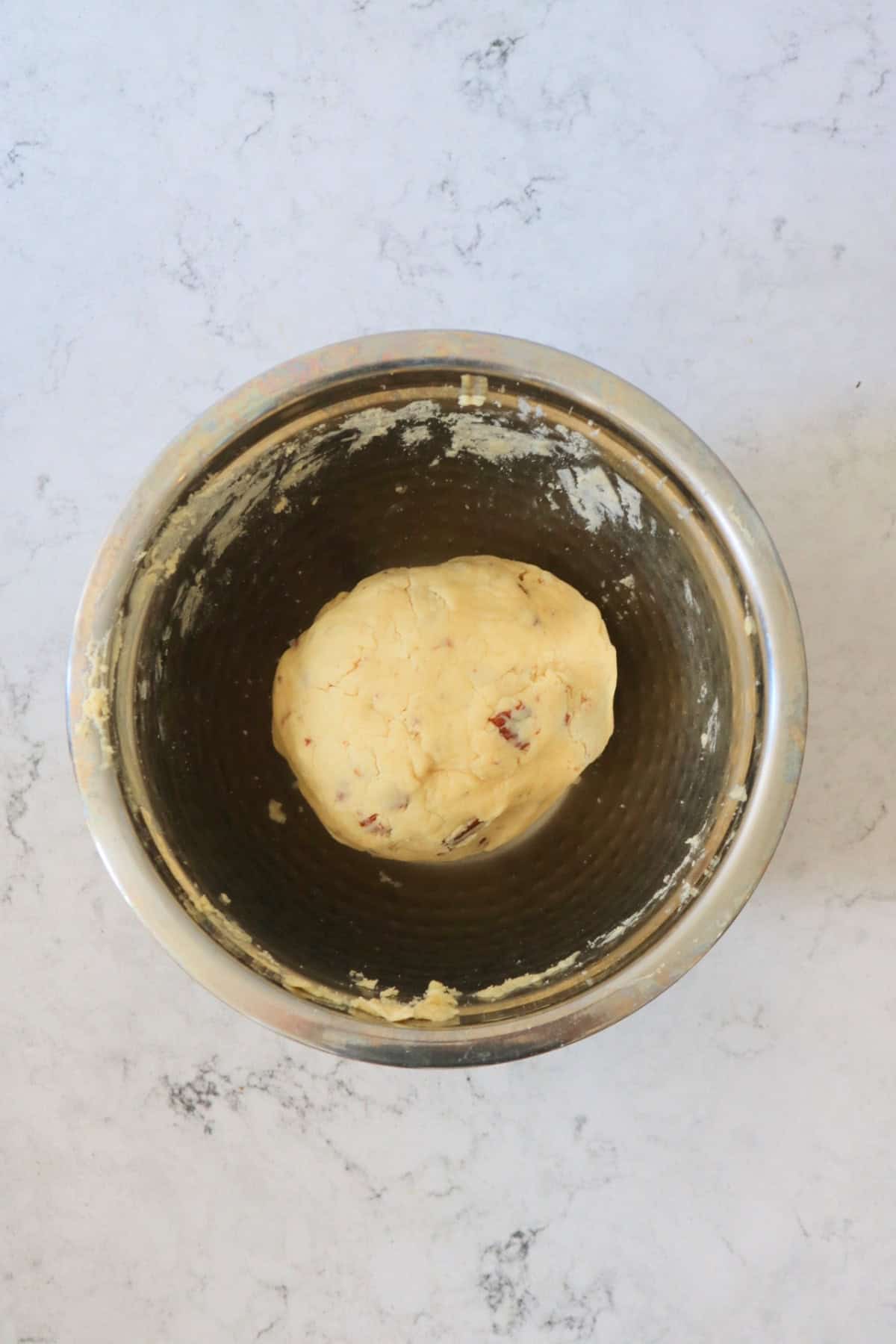 A ball of Vegan Pumpkin Spice and Pecan Cookie dough in a metal mixing bowl