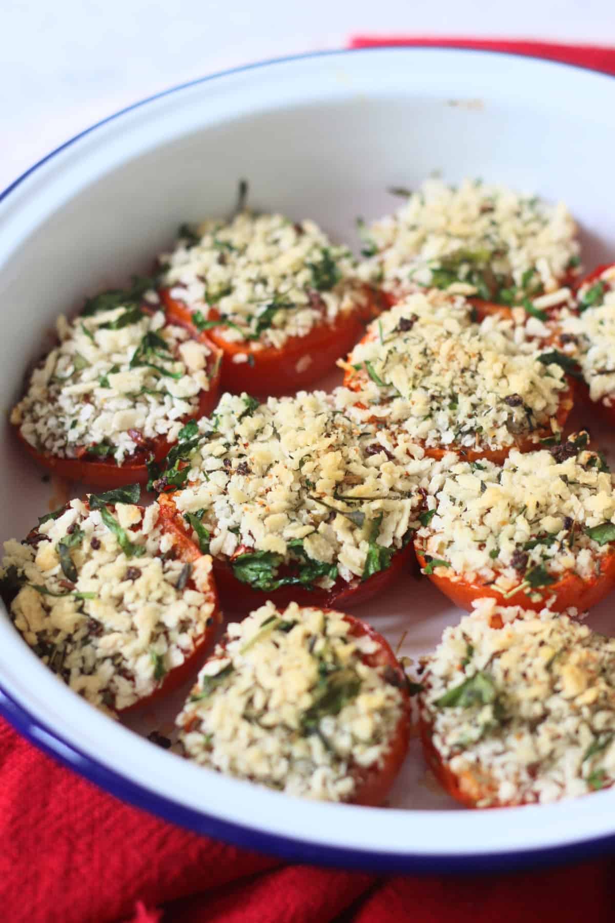 Breadcrumb and herb topped Tomates à la Provençale (Provence Style Tomatoes) in a white and blue enamel dish with a red napkin