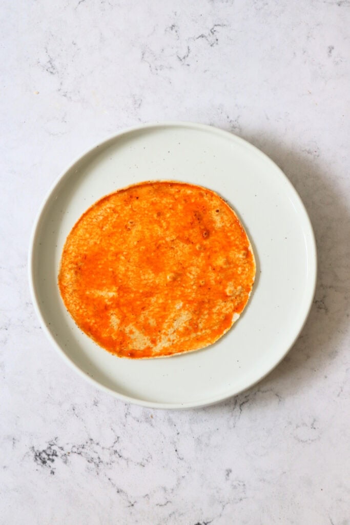 A corn tortilla dipped in chilli oil