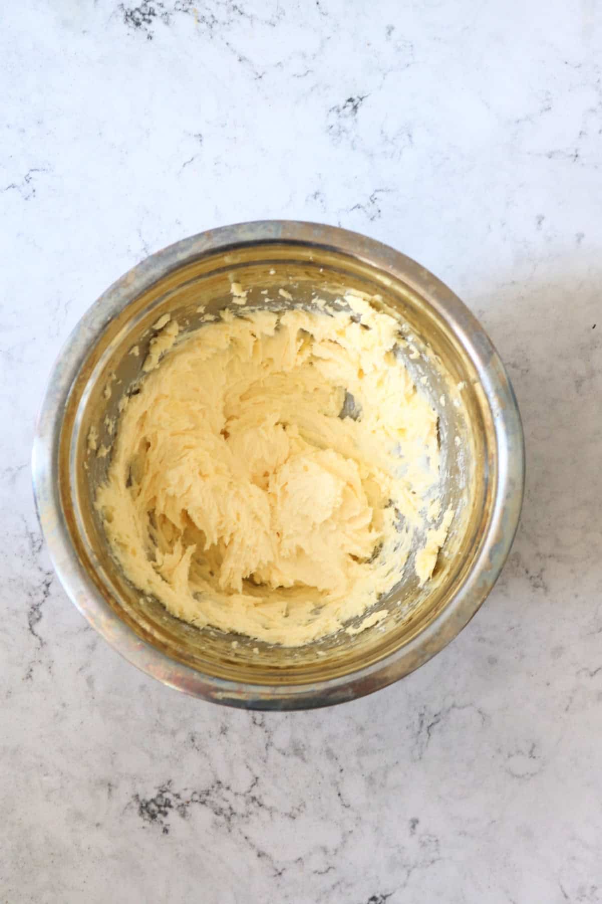 Vegan butter and sugar creamed together in a metal mixing bowl