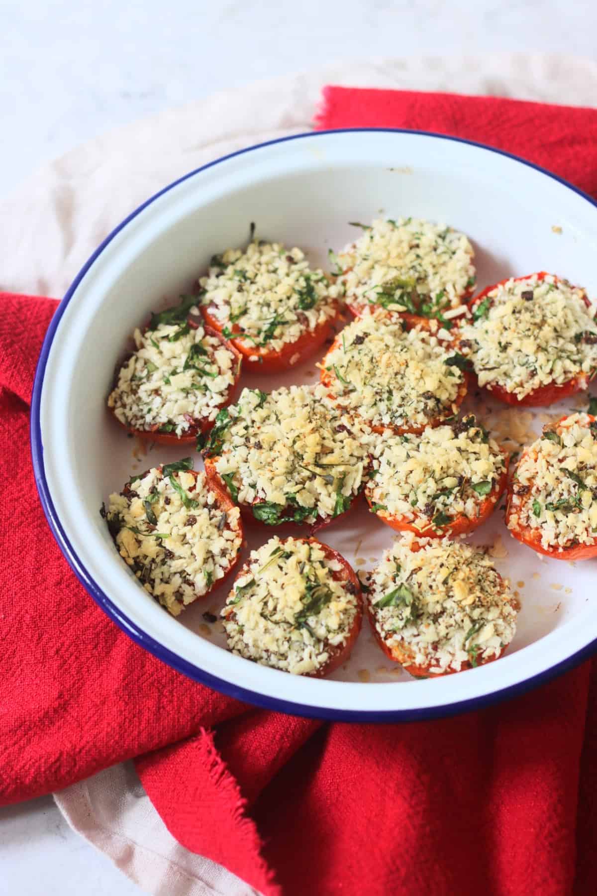 Breadcrumb and herb topped Tomates à la Provençale (Provence Style Tomatoes) in a white and blue enamel dish with a red napkin