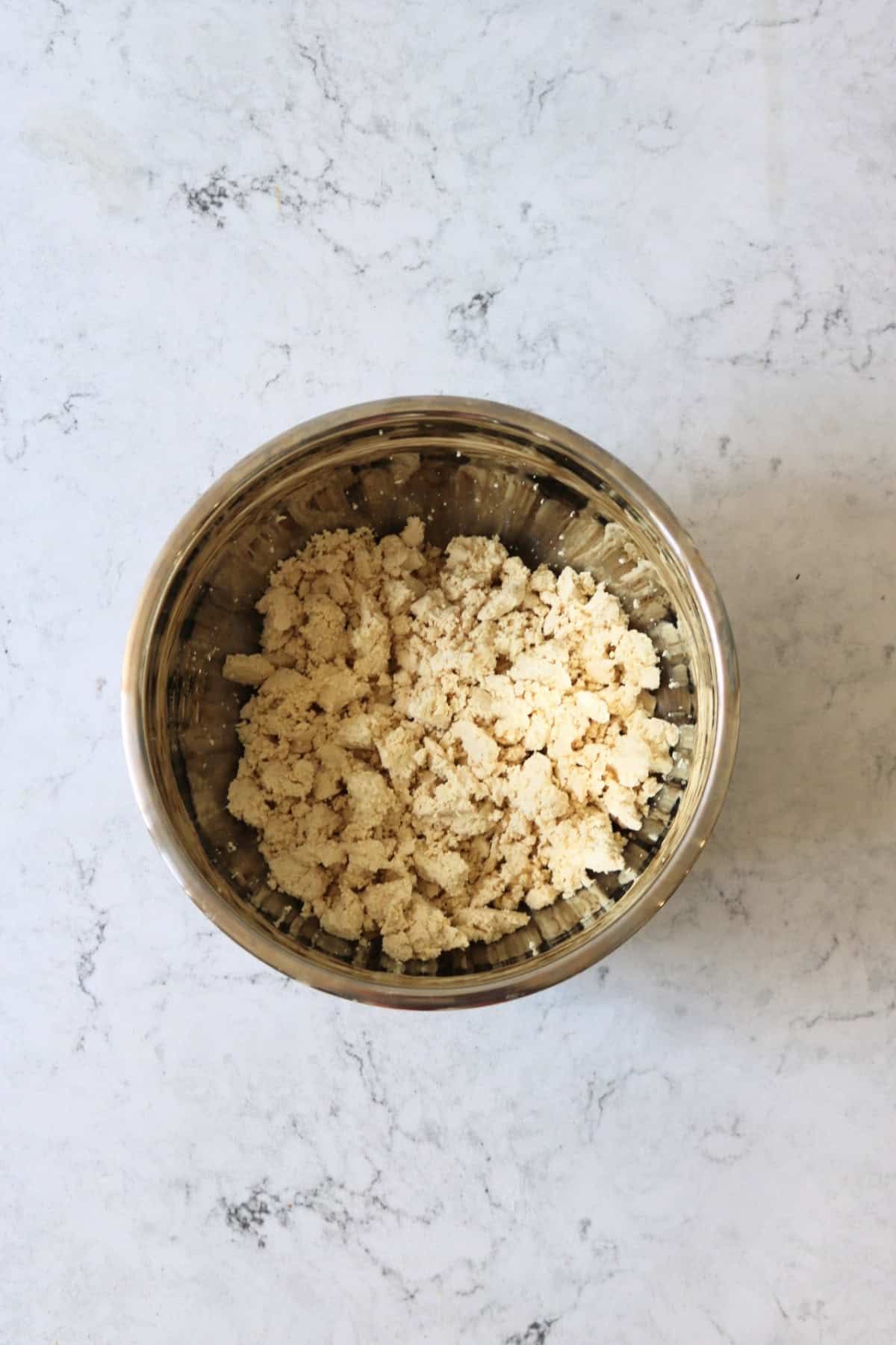 Crumbled tofu in a metal mixing bowl