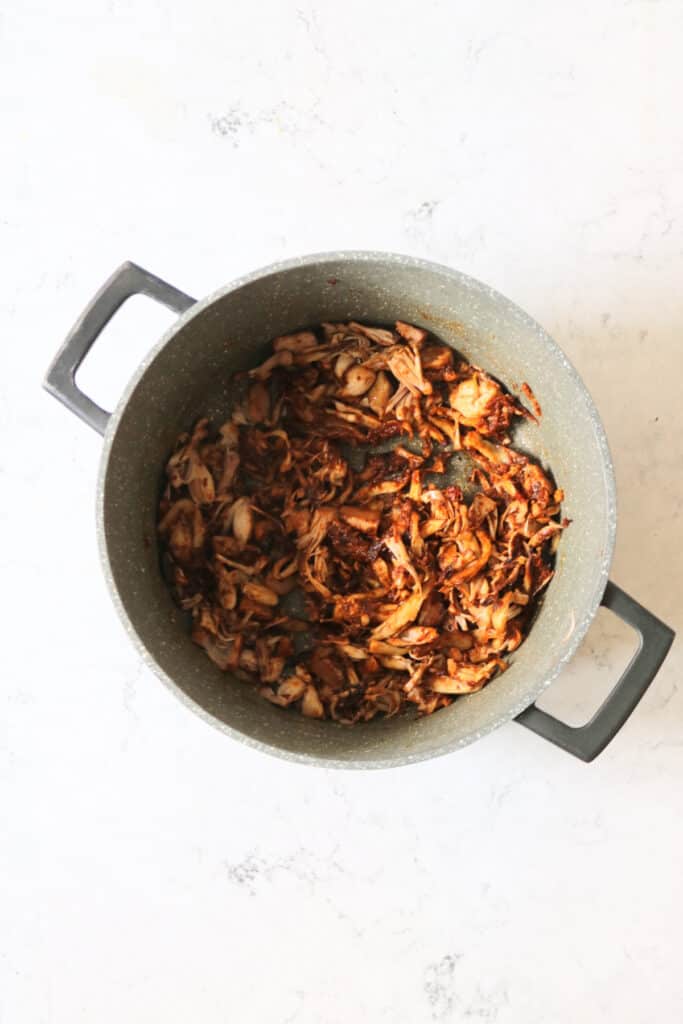 Shredded oyster mushrooms and jackfruit cooking in adobo sauce