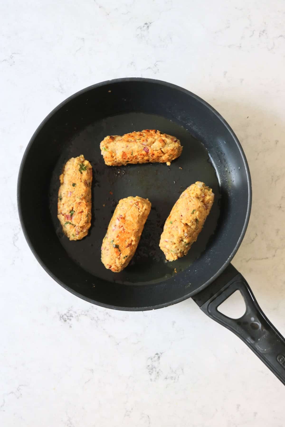 4 Vegan Tofu Kofta frying in a large flat bottomed saucepan