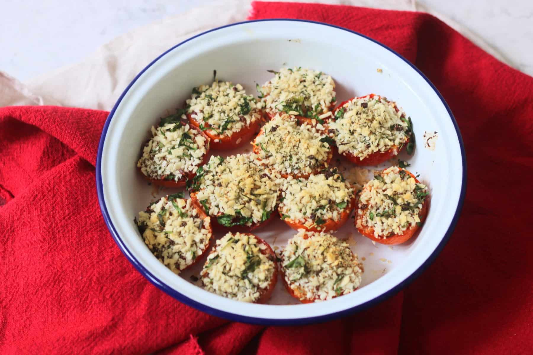 Breadcrumb and herb topped Tomates à la Provençale (Provence Style Tomatoes) in a white and blue enamel dish with a red napkin