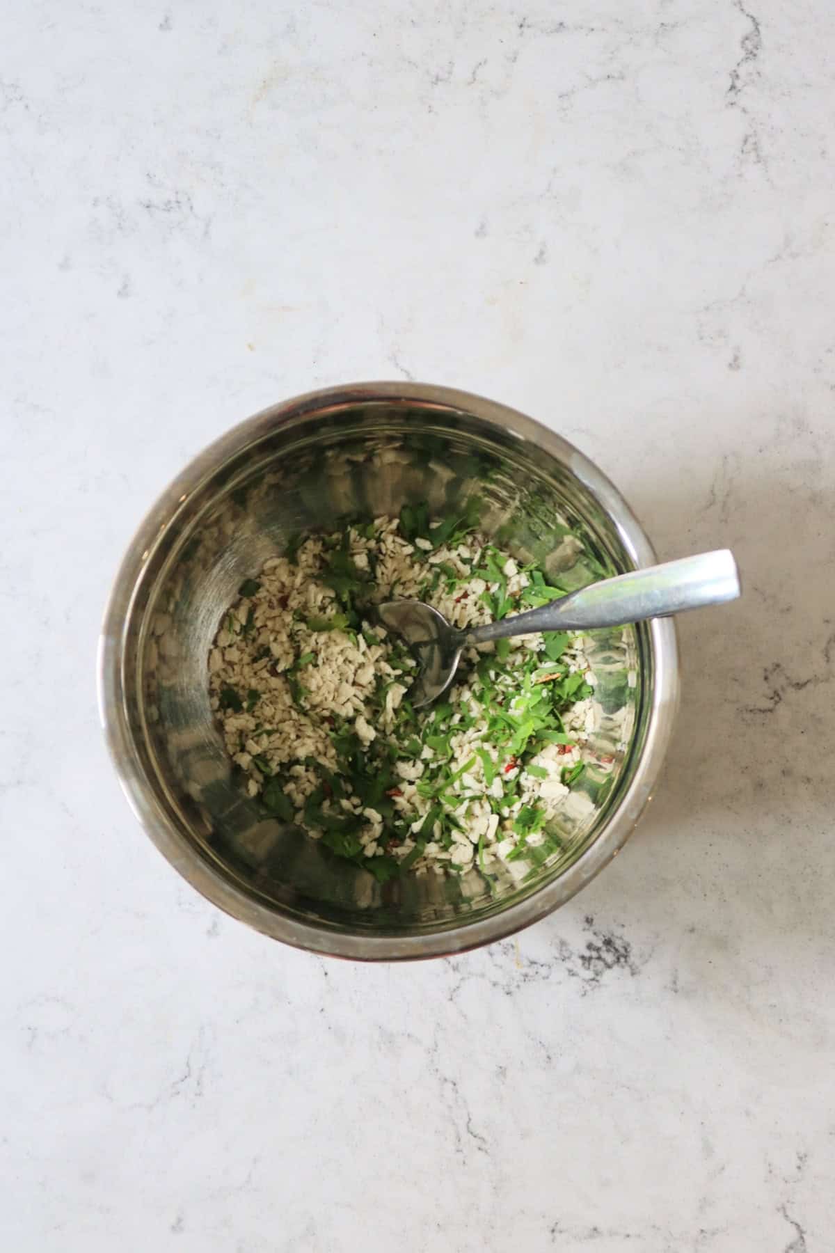 A breadcrumb and herb mixture to be used to make Tomates à la Provençale (Provence Style Tomatoes) in a metal mixing bowl