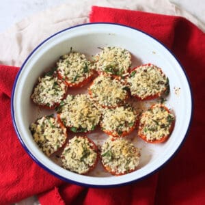 Breadcrumb and herb topped Tomates à la Provençale (Provence Style Tomatoes) in a white and blue enamel dish with a red napkin