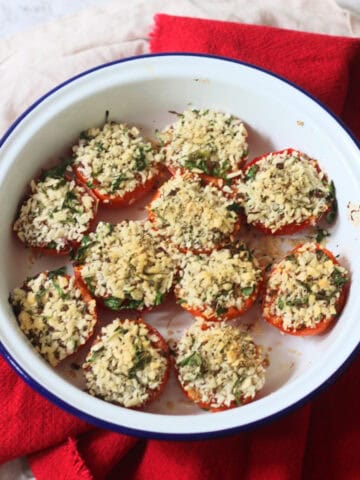 Breadcrumb and herb topped Tomates à la Provençale (Provence Style Tomatoes) in a white and blue enamel dish with a red napkin
