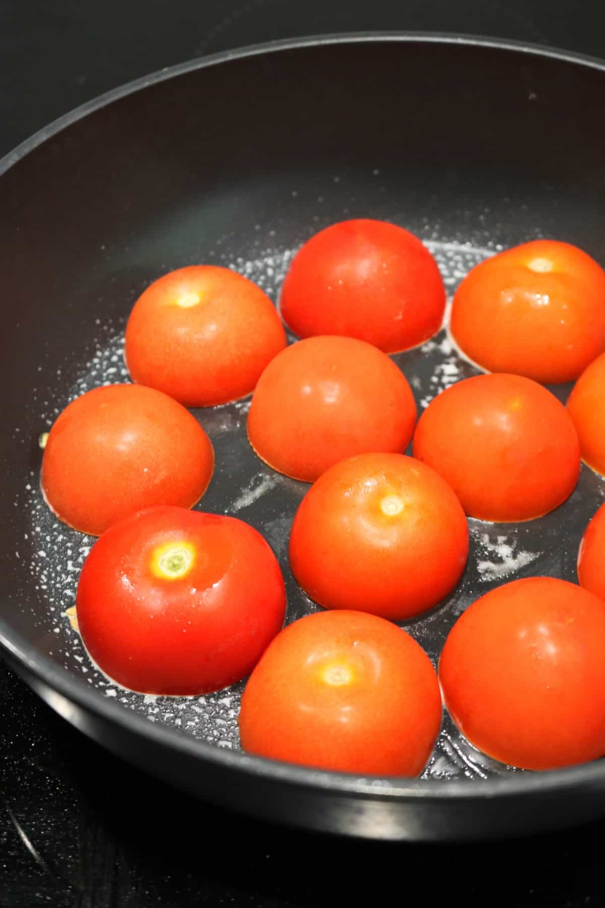 Tomatoes cooking cut side down in a large flat-bottomed frying pan for Tomates à la Provençale (Provence Style Tomatoes)