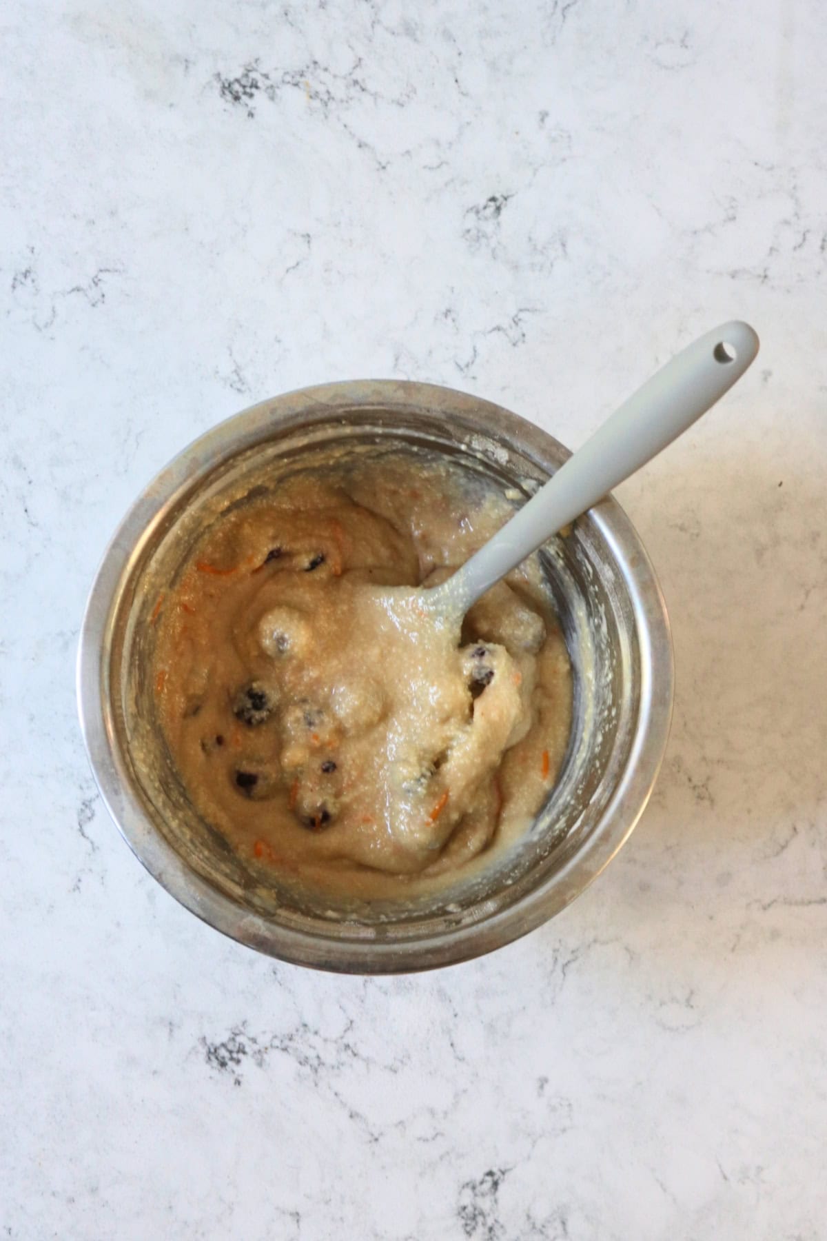 Vegan Blackberry and Orange Friand batter in a metal mixing bowl with a grey spatula