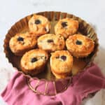 Seven Vegan Blackberry and Orange Friands on a gold cake stand sat on top of a pink and white napkin