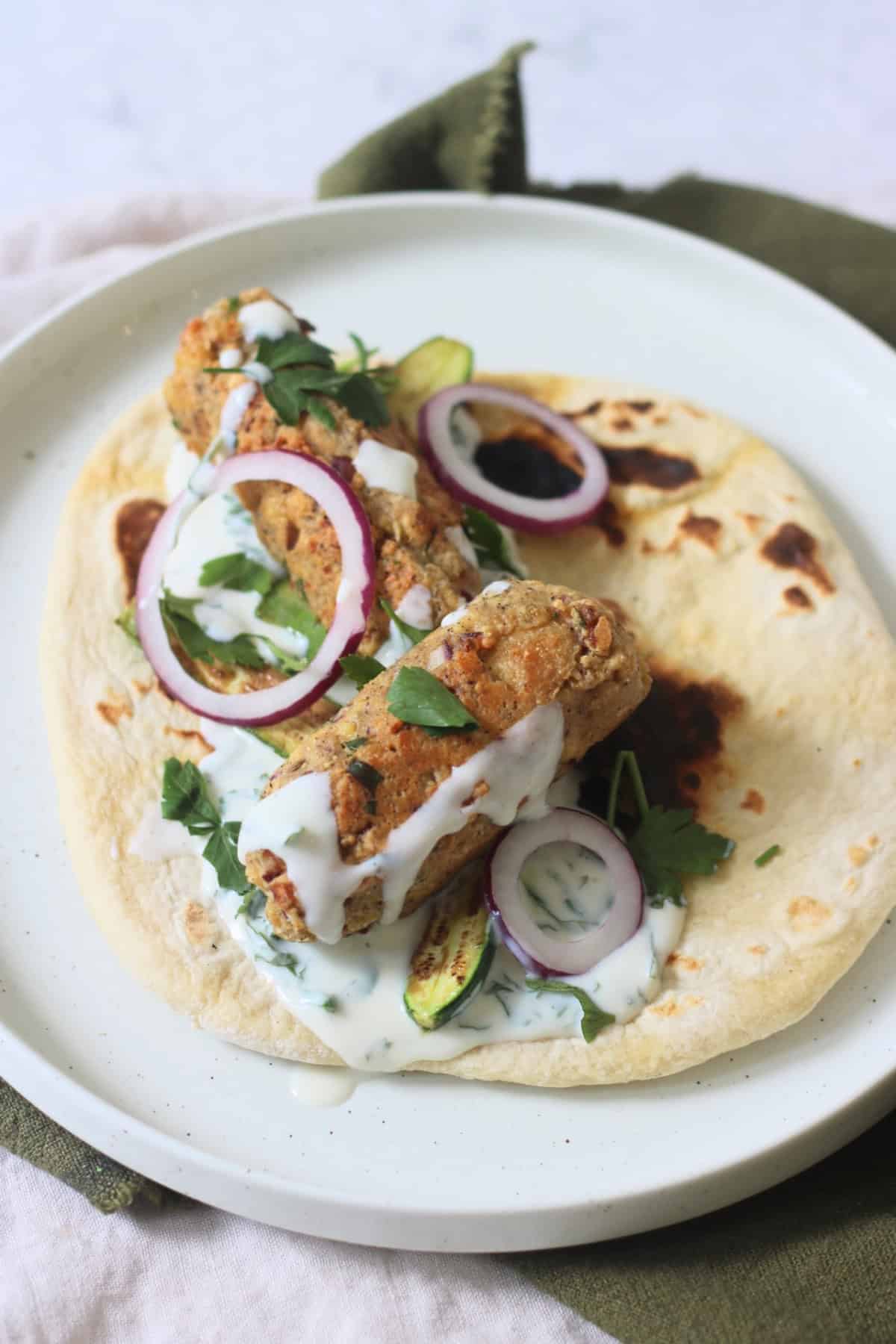 2 Vegan Tofu Kofta with mint yogurt, red onion and baby courgettes served on a flatbread