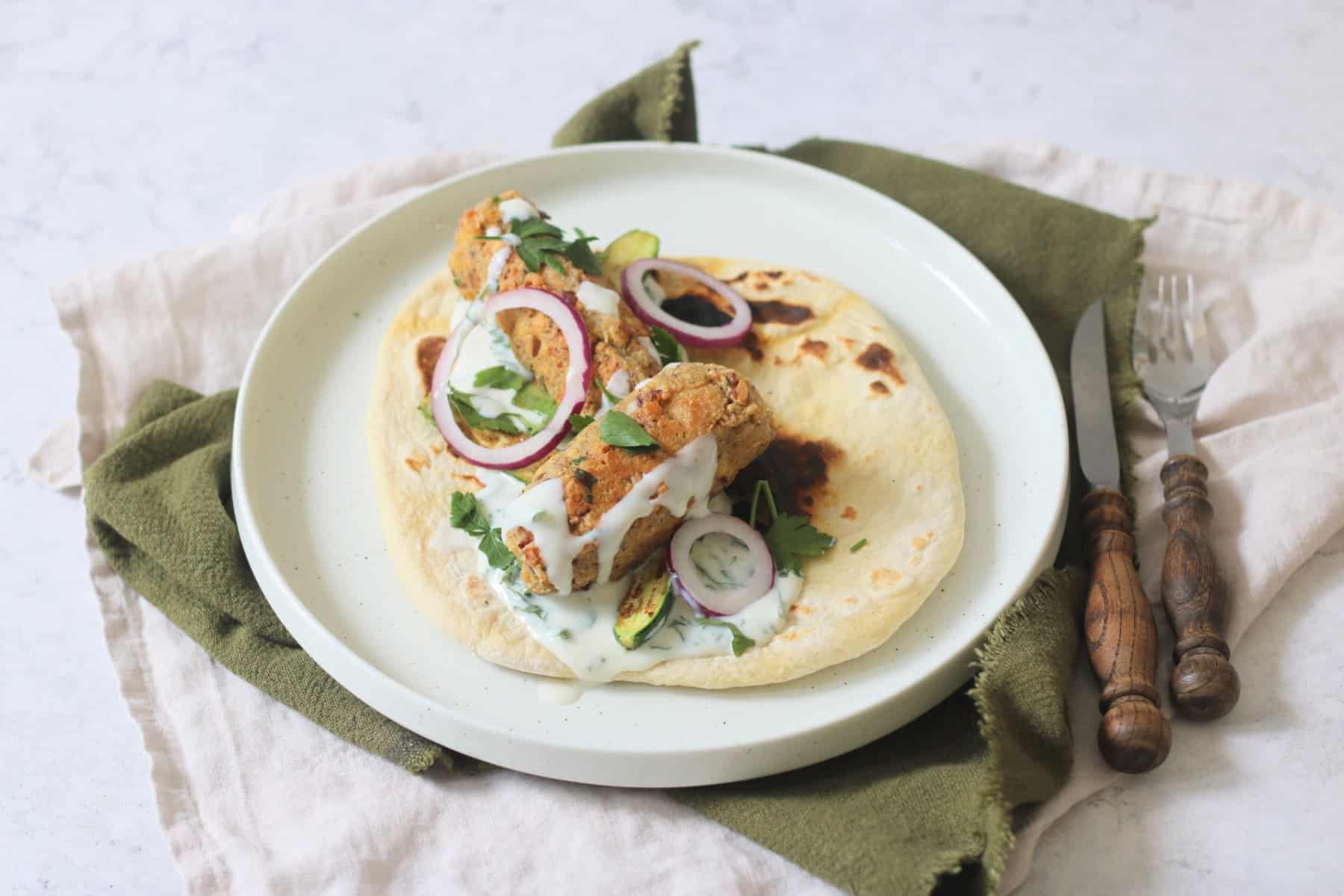 2 Vegan Tofu Kofta with mint yogurt, red onion and baby courgettes served on a flatbread