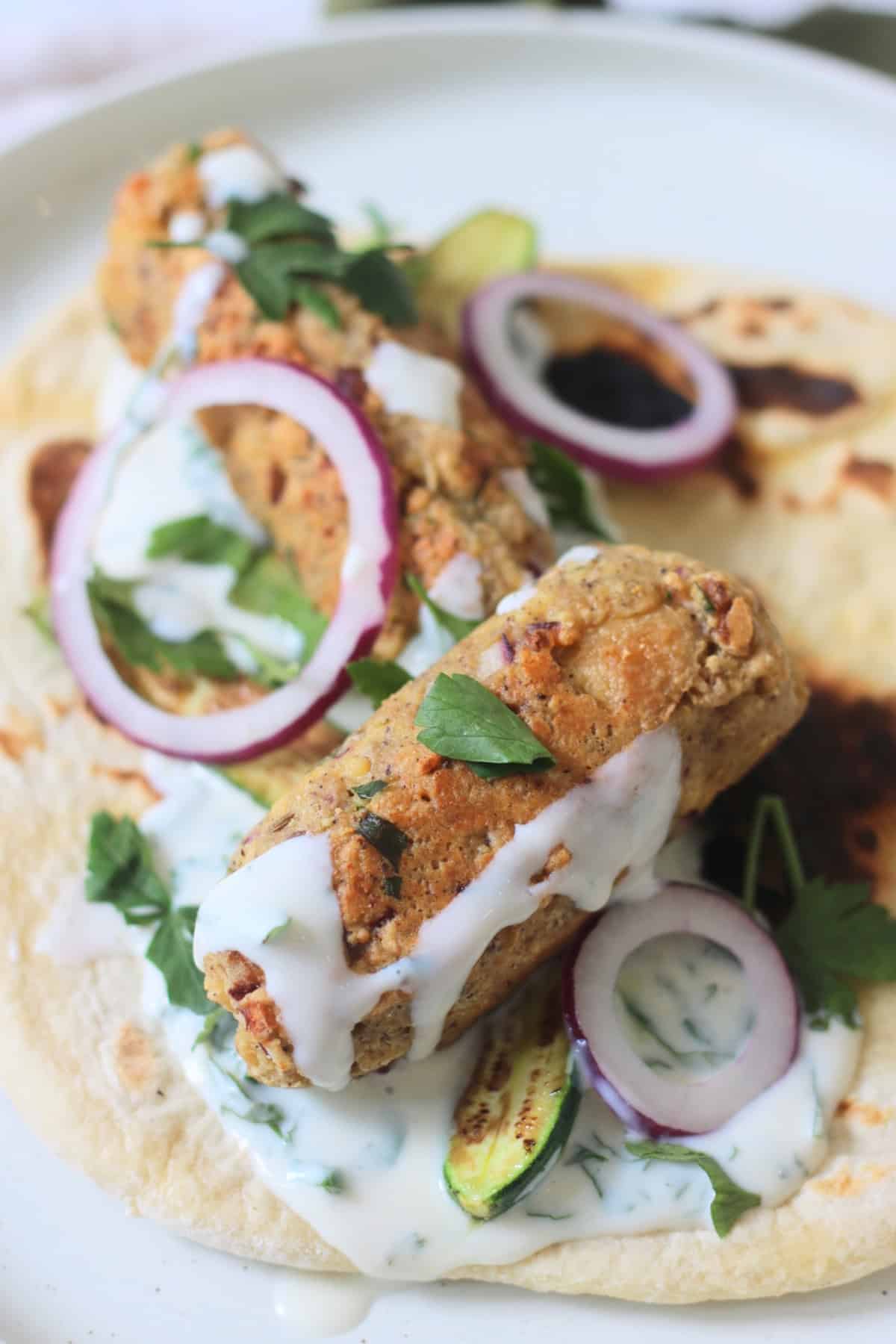 2 Vegan Tofu Kofta with mint yogurt, red onion and baby courgettes served on a flatbread