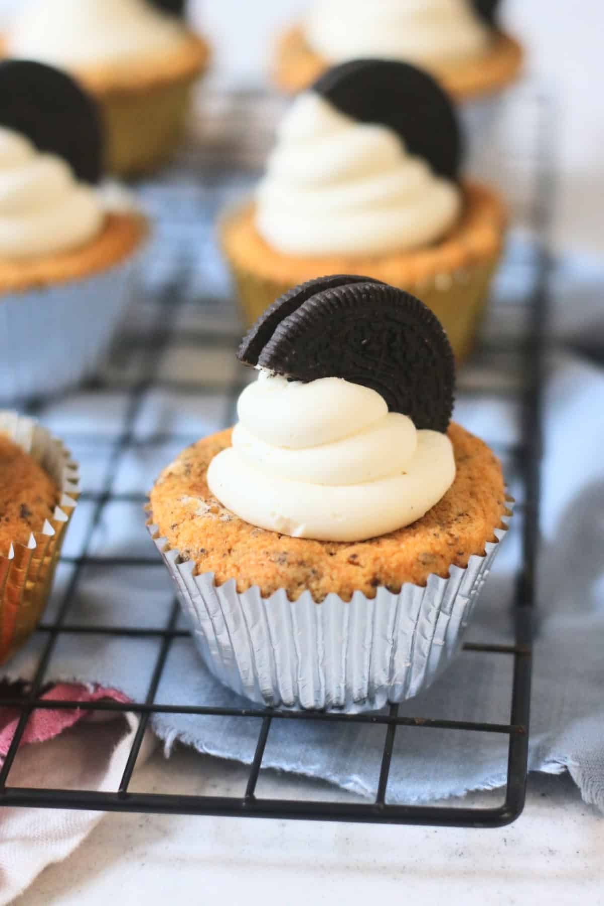 A close up of a Vegan Oreo Cookies and Cream Cupcake in a silver cupcake case with half an oreo pressed into a mound of buttercream icing