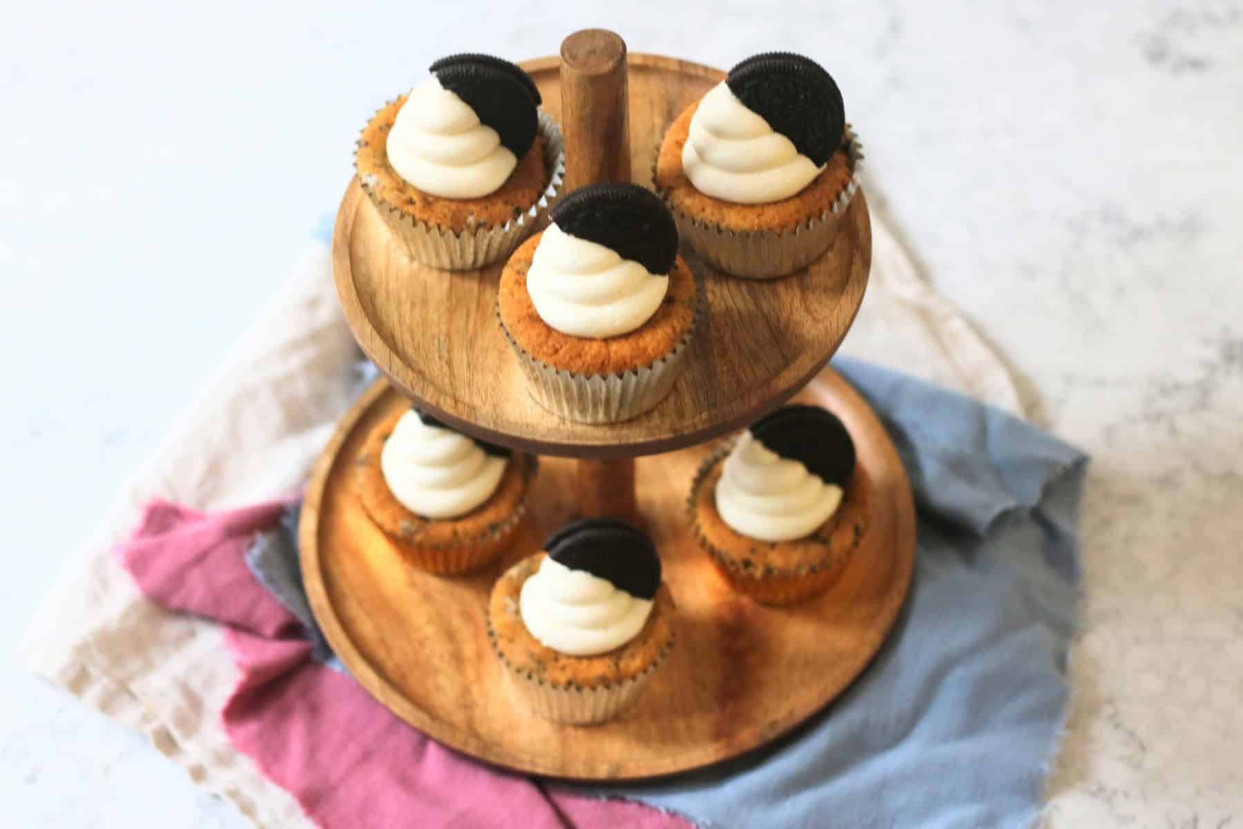 Vegan Oreo Cookies and Cream Cupcakes laid out on a wooden cake stand
