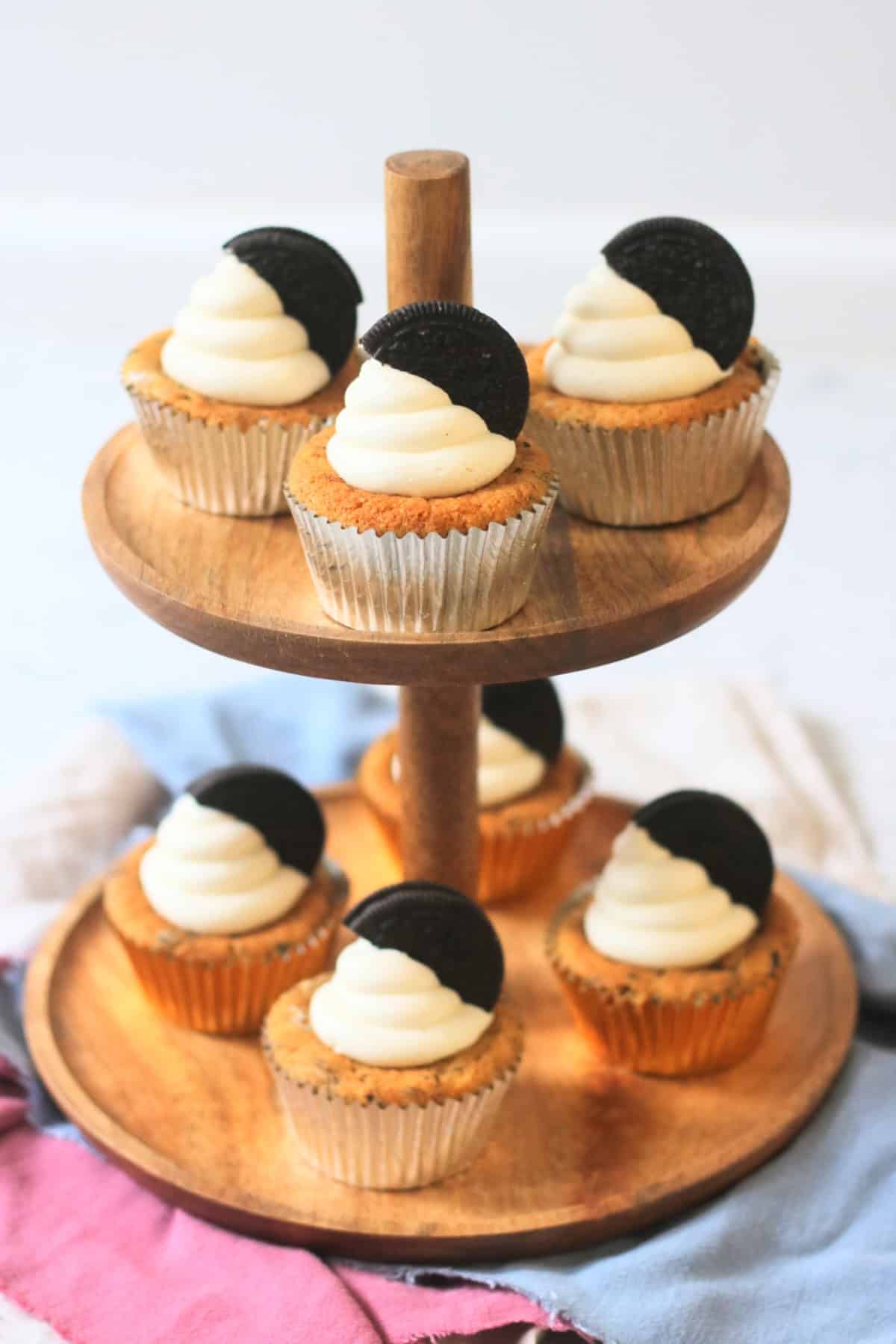 Vegan Oreo Cookies and Cream Cupcakes laid out on a wooden cake stand
