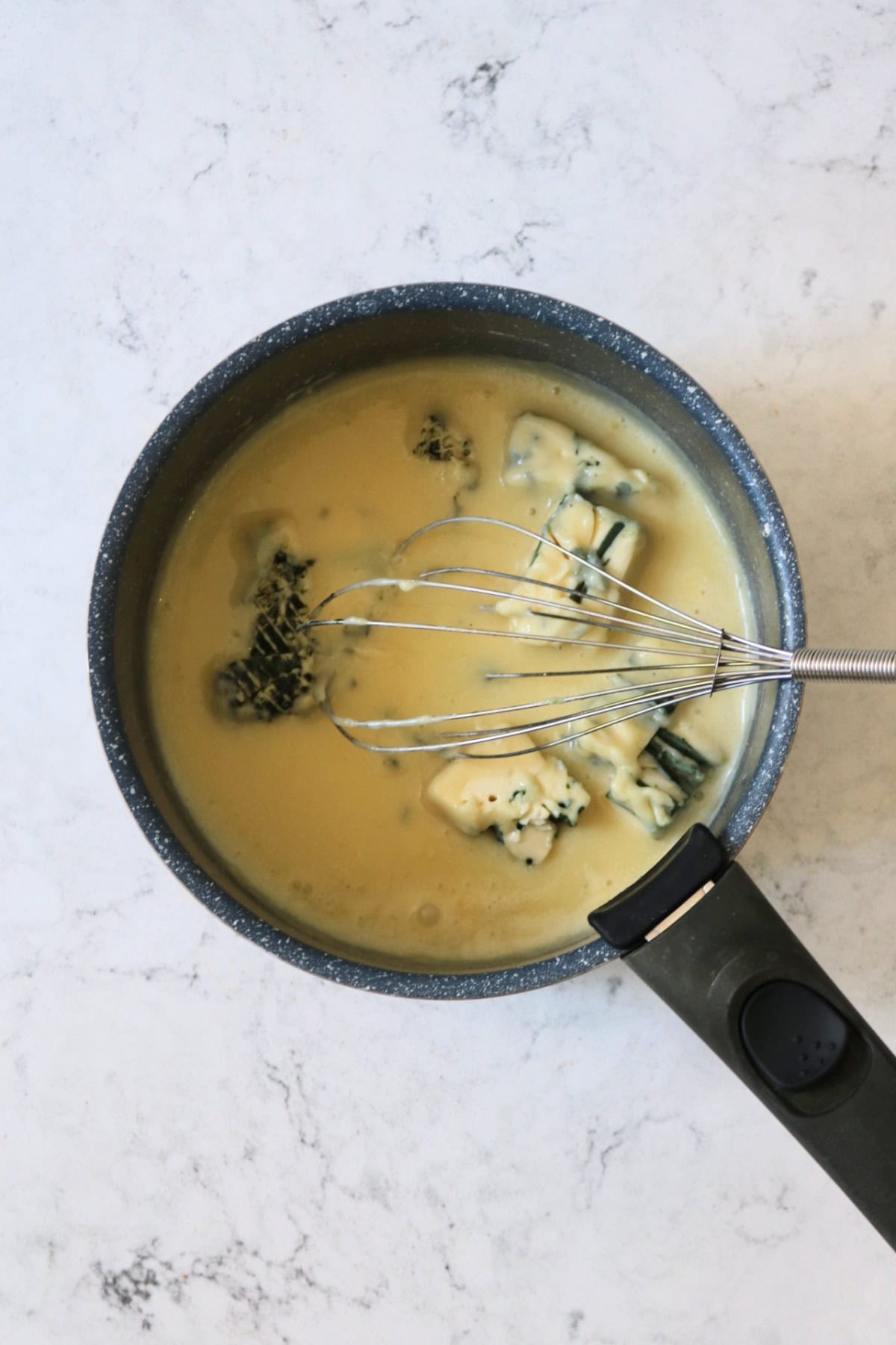 Vegan blue cheese being whisked into bechamel sauce