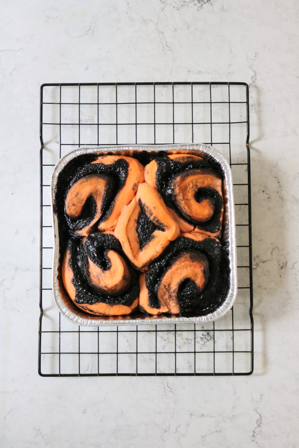 Vegan Halloween Pumpkin Spice Rolls in a foil tray sat on a wire rack
