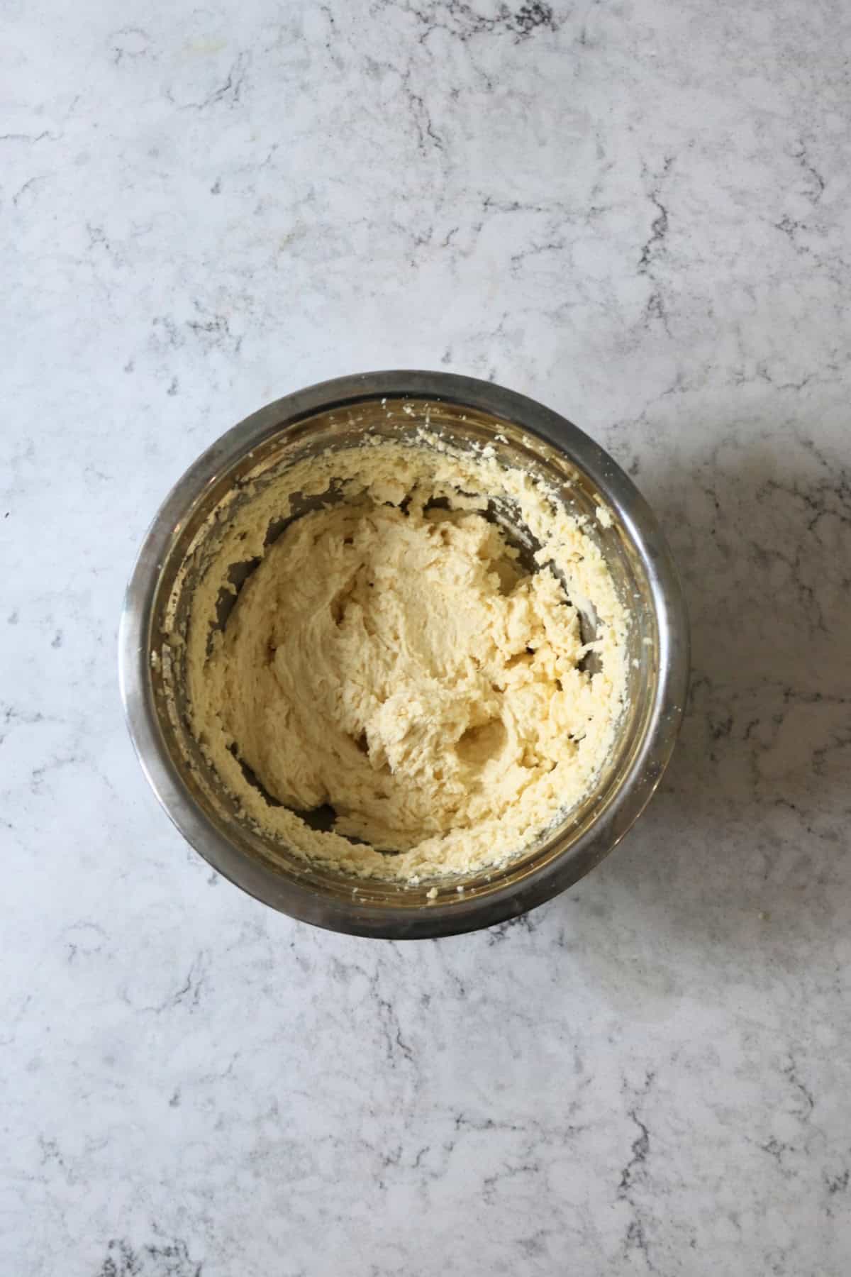 Beating together wet ingredients, vegan butter and sugar in a large metal mixing bowl