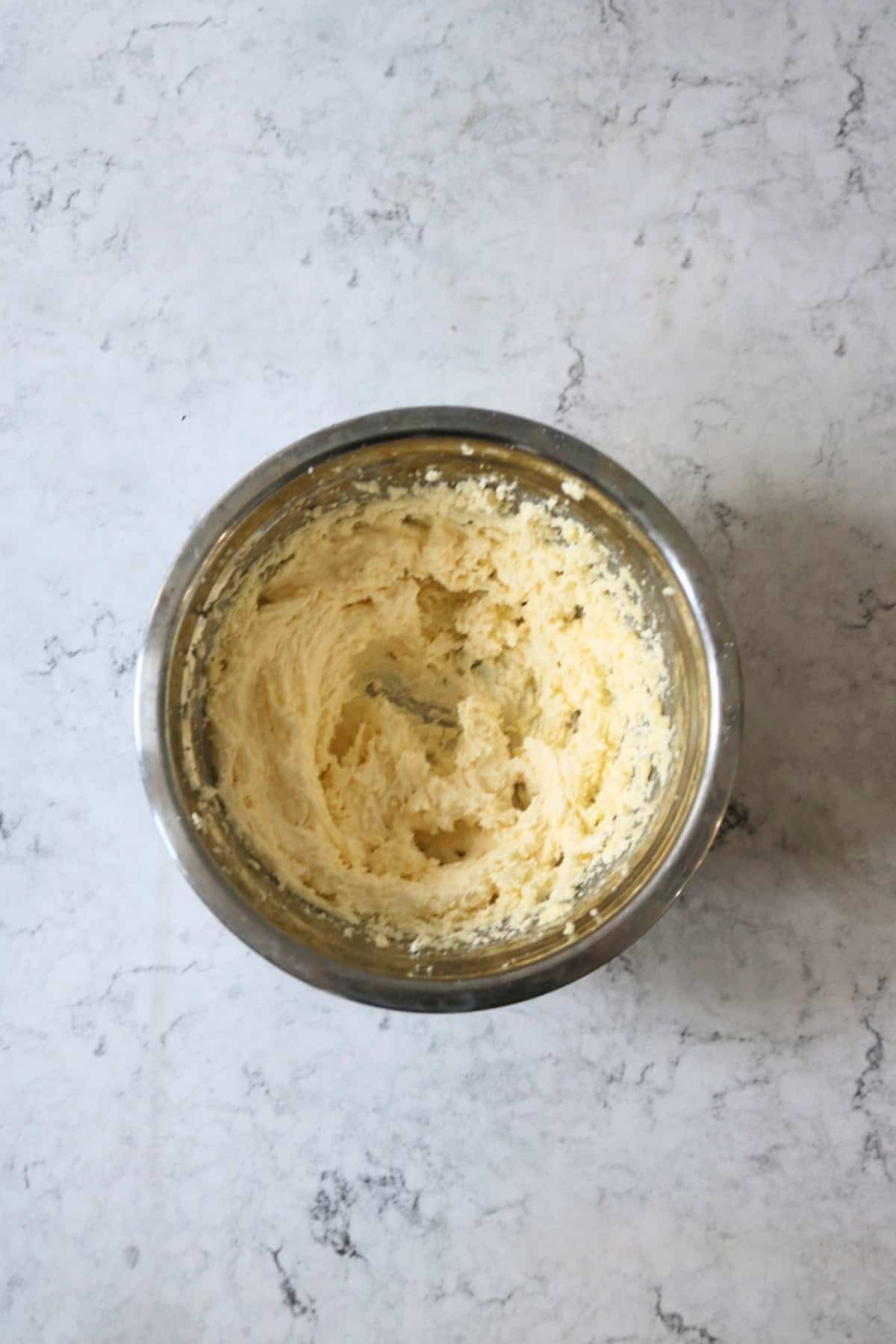 Creaming together vegan butter and sugar in a large metal mixing bowl