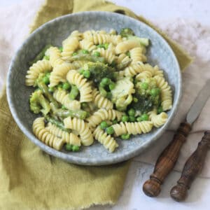 Vegan Blue Cheese Pasta with Spring Greens served with wooden handled knife and fork and a green napkin