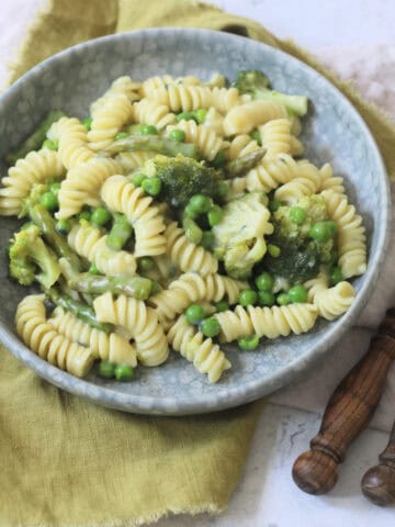 Vegan Blue Cheese Pasta with Spring Greens served with wooden handled knife and fork and a green napkin
