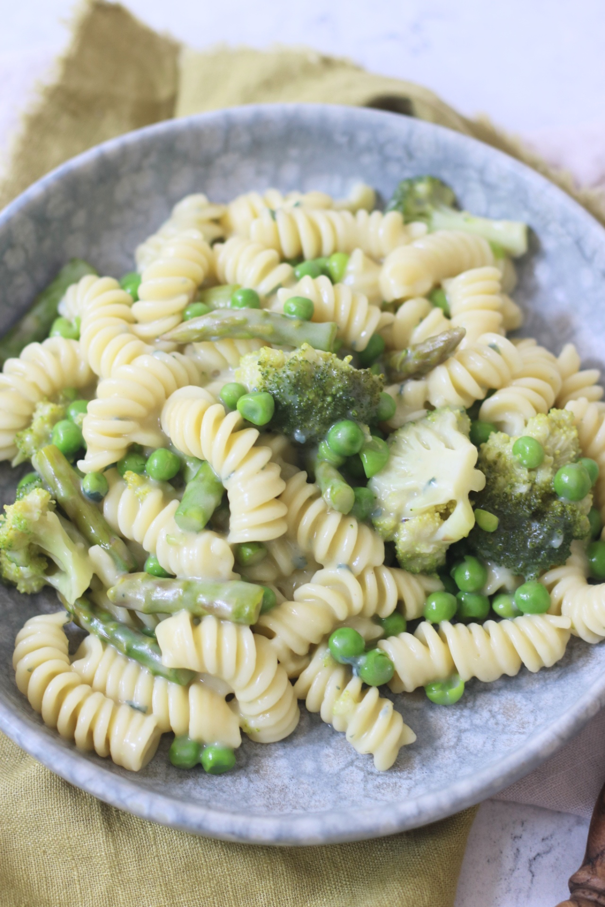Vegan Blue Cheese Pasta with Spring Greens served on a grey plate with a green napkin