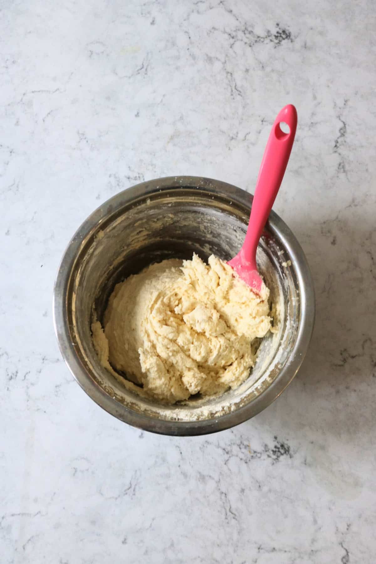 Folding in flour to vegan cupcake batter using a bright pink spatula