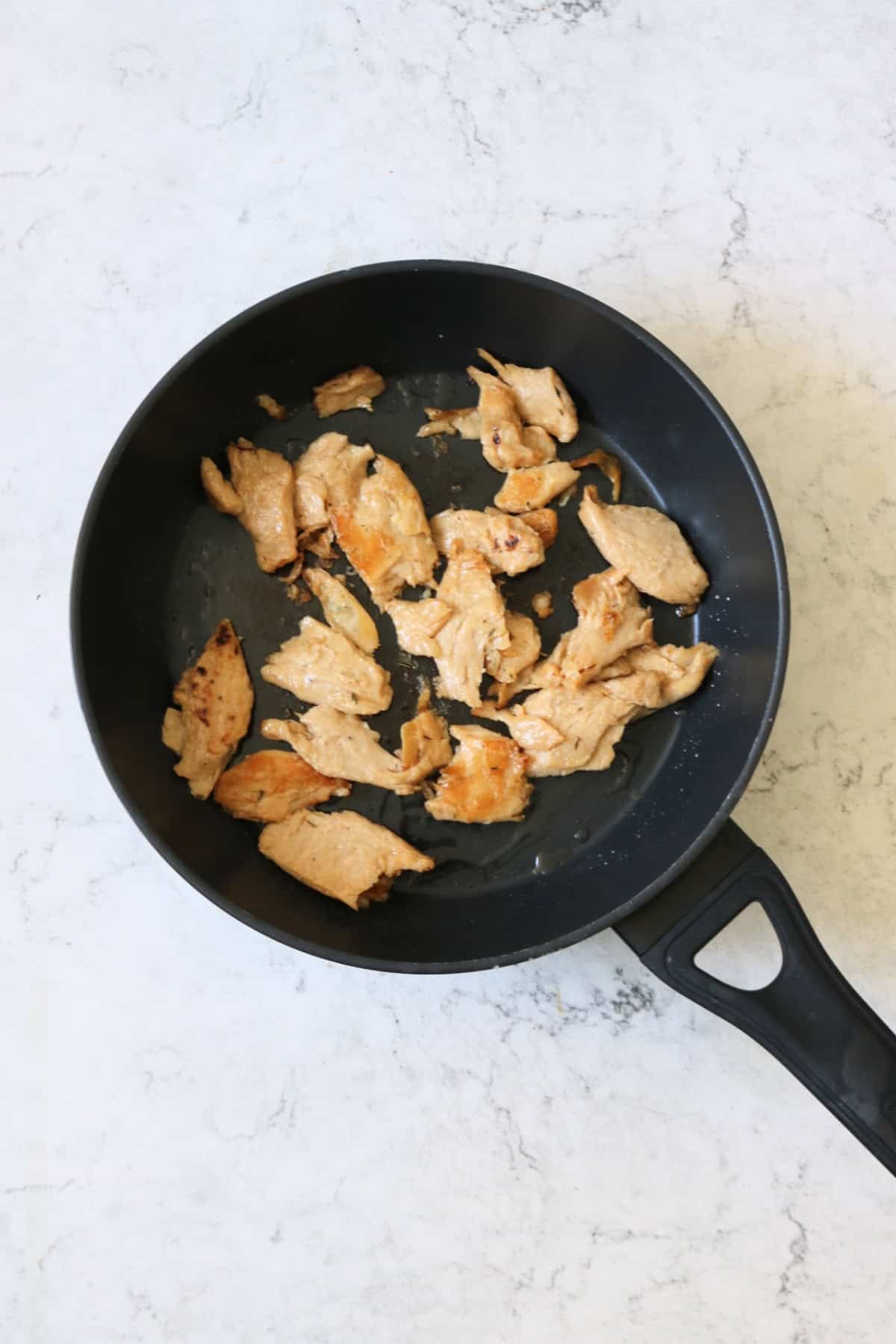 Frying vegan chicken pieces in a large flat bottomed frying pan