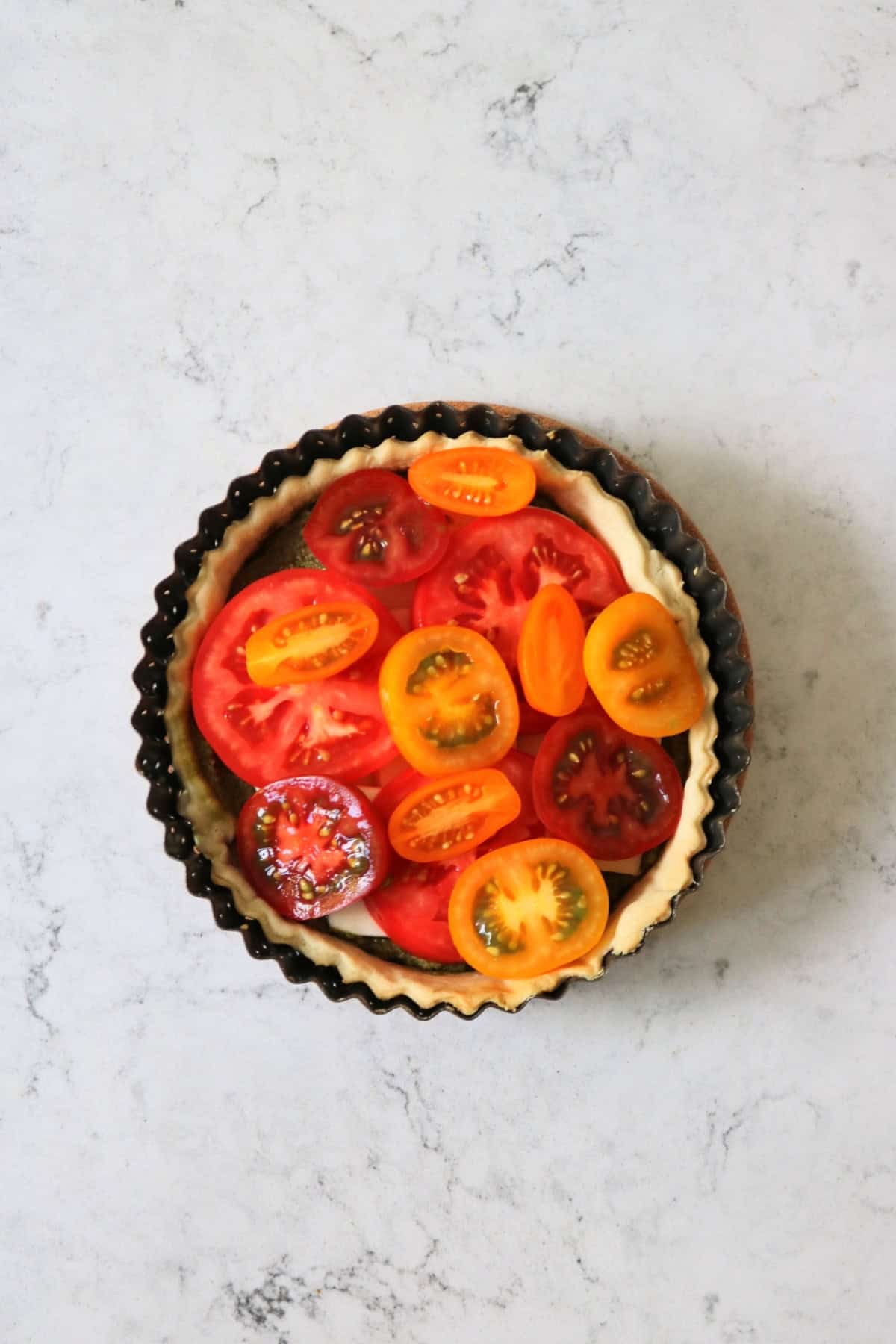 Pastry case with pesto, mozzarella and tomatoes, ready to go in the oven