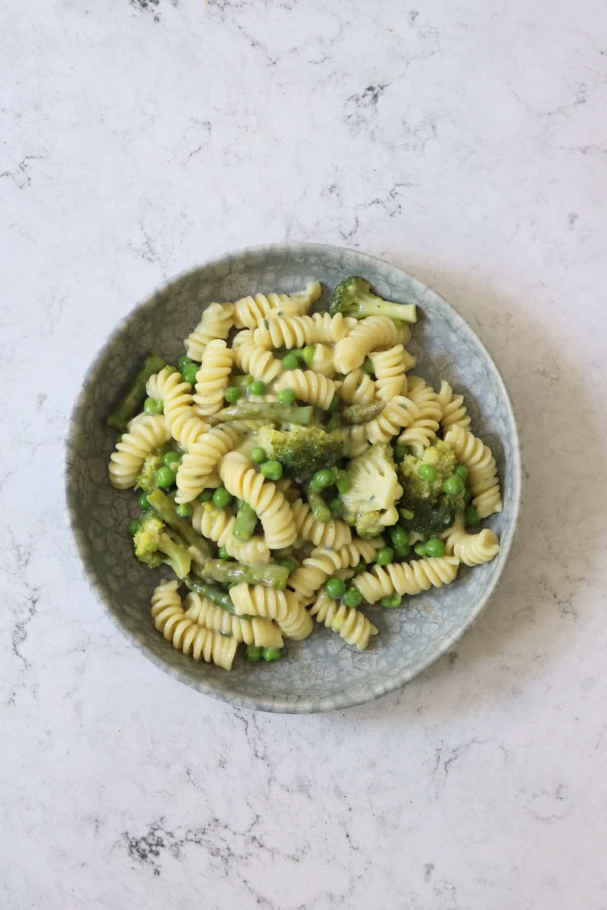 Vegan Blue Cheese Pasta with Spring Greens served on a grey plate