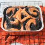 Vegan Halloween Pumpkin Spice Rolls in a foil tray sat on a wire rack