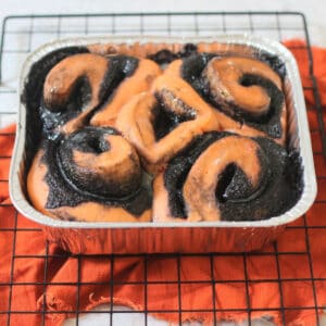 Vegan Halloween Pumpkin Spice Rolls in a foil tray sat on a wire rack
