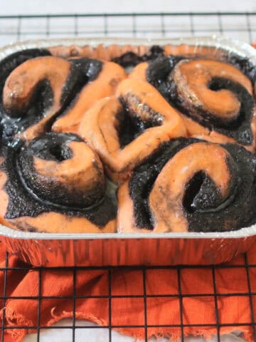 Vegan Halloween Pumpkin Spice Rolls in a foil tray sat on a wire rack