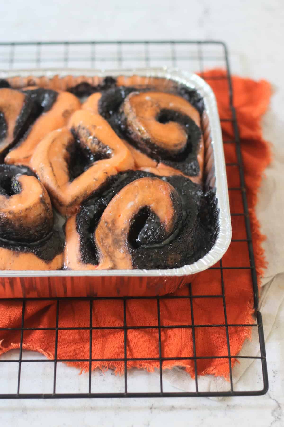 Vegan Halloween Pumpkin Spice Rolls in a foil tray sat on a wire rack