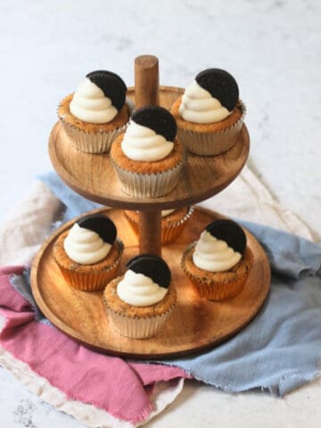 Vegan Oreo Cookies and Cream Cupcakes laid out on a wooden cake stand