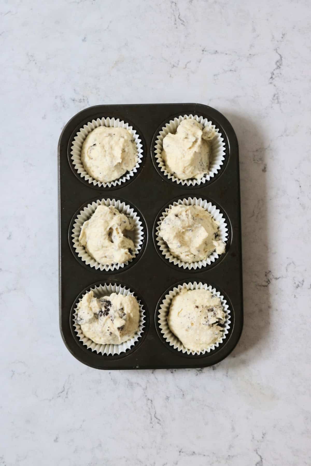 6 Vegan Oreo Cookies and Cream Cupcakes in the tin ready for baking