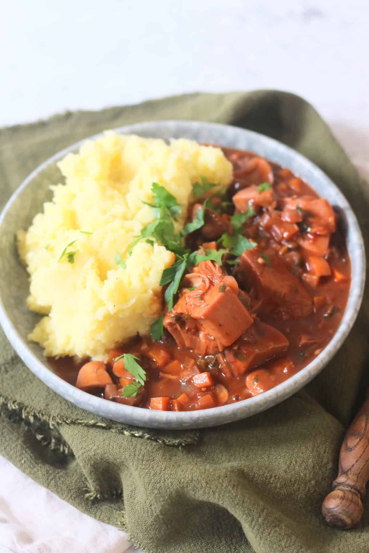 A plate of Vegan Coq Au Vin served alongside fluffy mashed potatoes