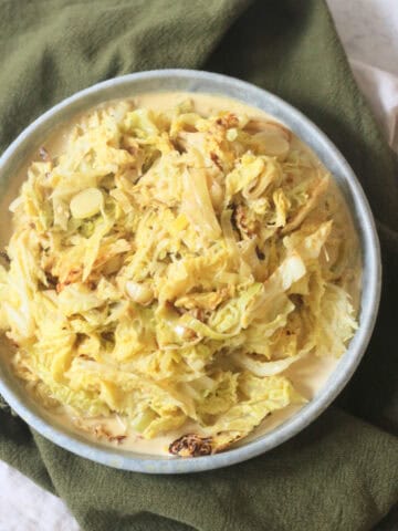 A side dish of Vegan Creamed Cabbage and Leeks served with a dark green napkin