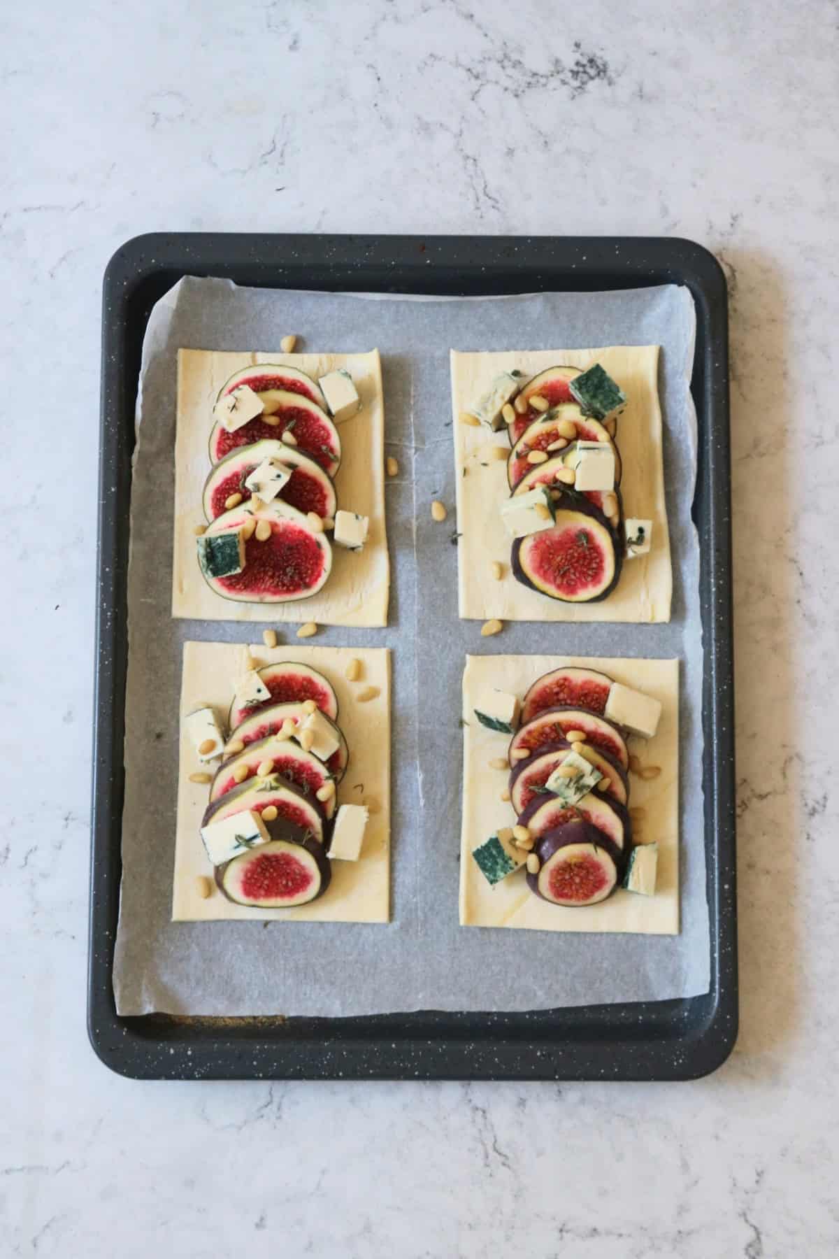 Four unbaked Vegan Fig and Blue Cheese Tarts on a baking tray lined with baking paper