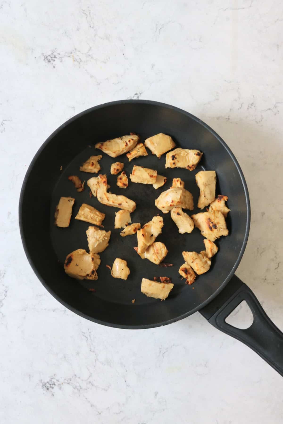 Frying vegan chicken pieces in a large frying pan