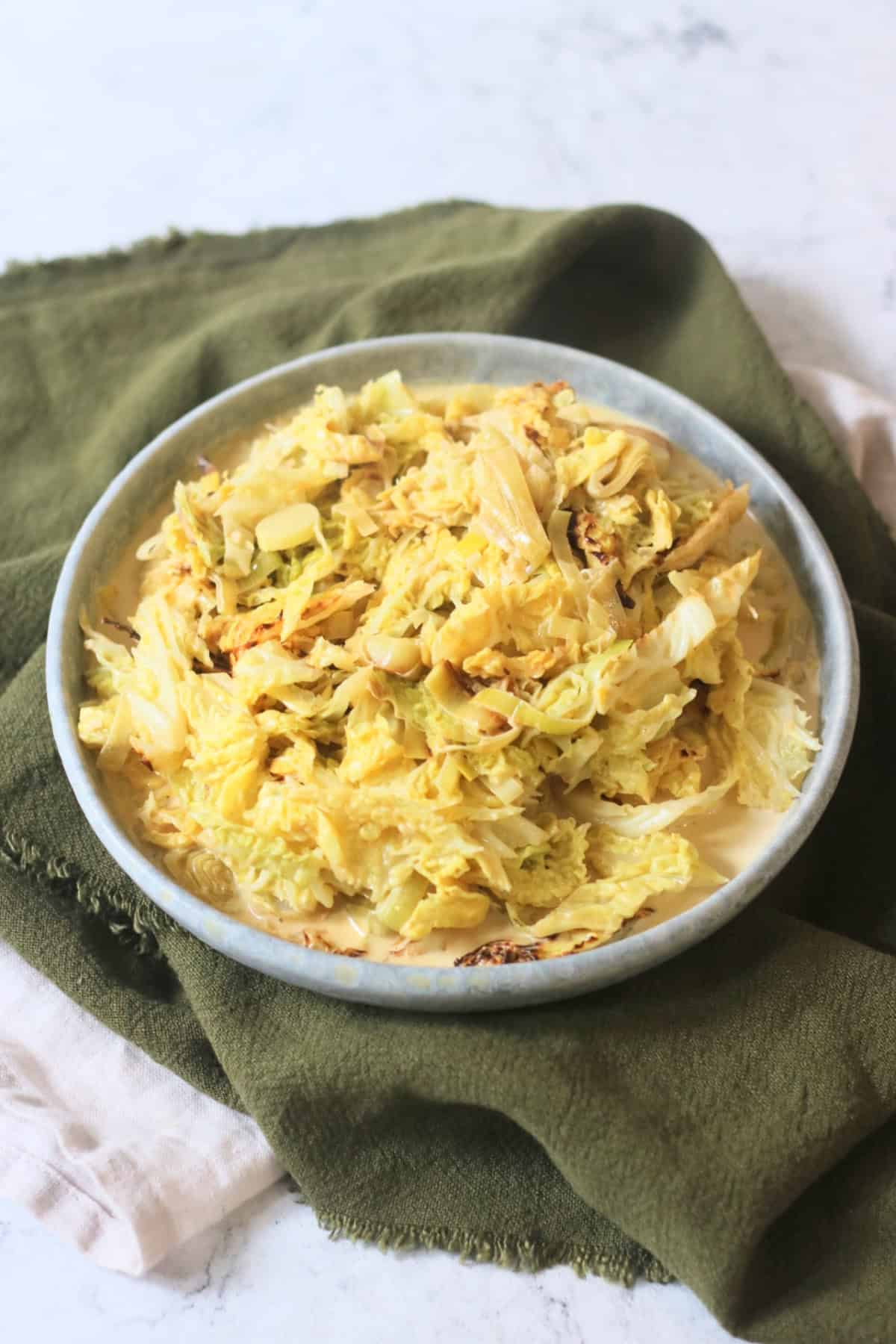 A side dish of Vegan Creamed Cabbage and Leeks served with a dark green napkin