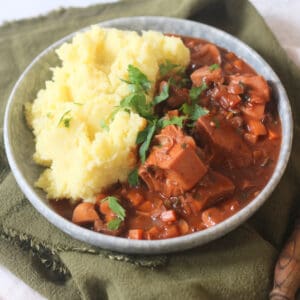 A plate of Vegan Coq Au Vin served alongside fluffy mashed potatoes
