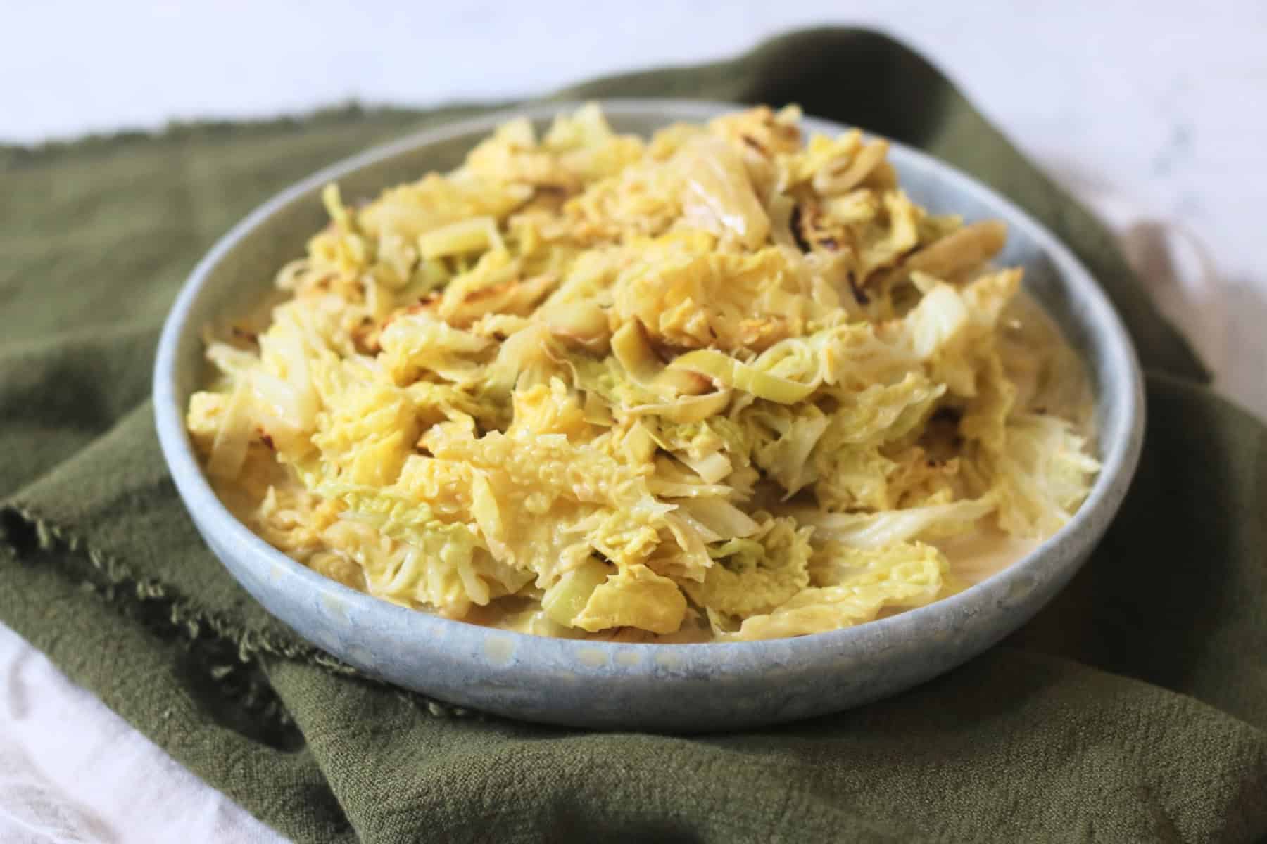 A side dish of Vegan Creamed Cabbage and Leeks served with a dark green napkin