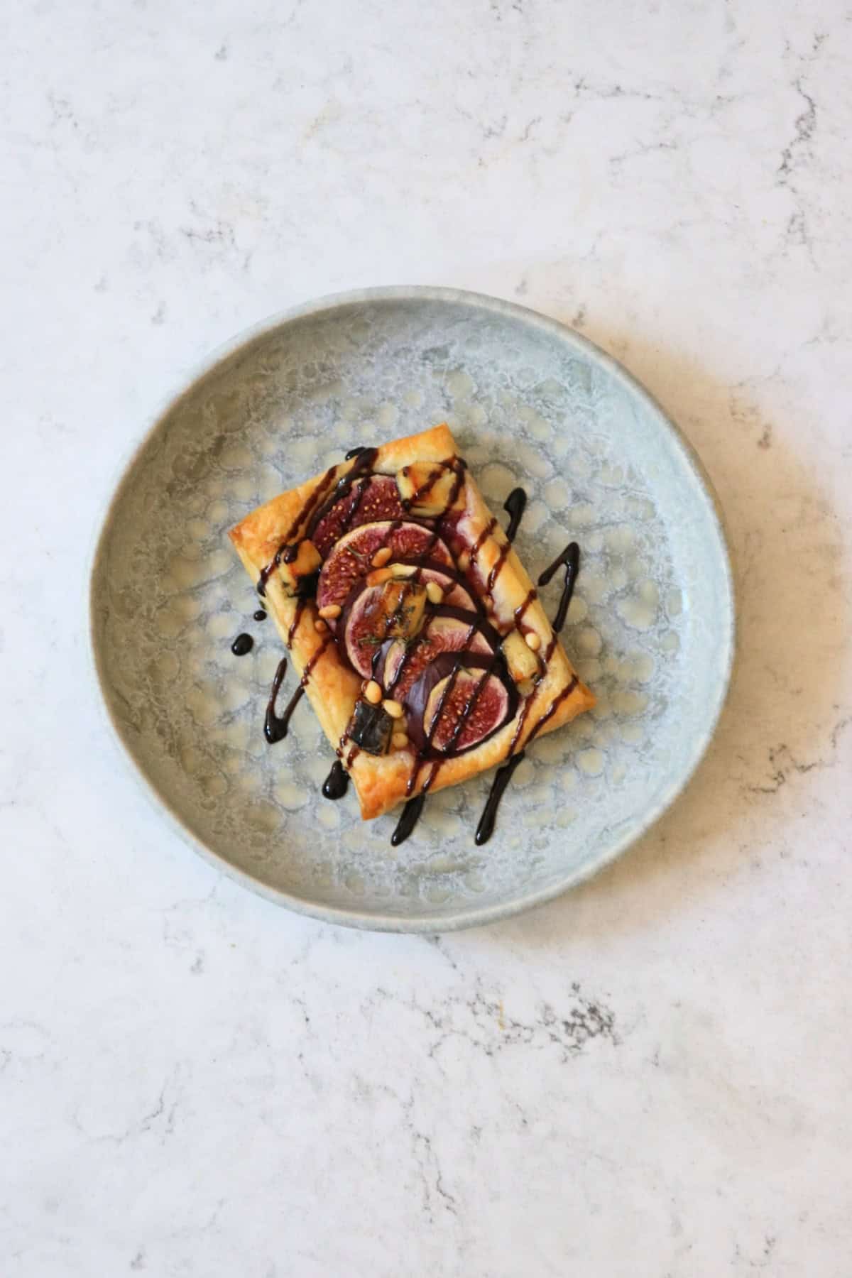 A Vegan Fig and Blue Cheese Tart drizzled with balsamic glaze on a plate